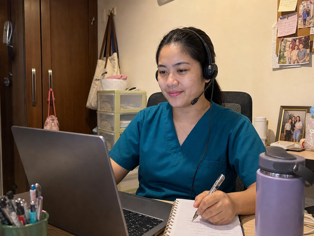 Filipino registered nurse virtual assistant working from a compact apartment bedroom workspace with a laptop and headset.